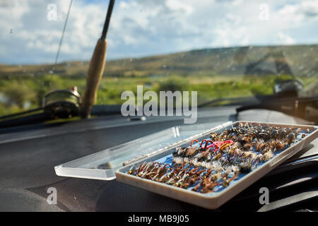 Opened box of specialist flies for fly fishing inside a car with a rod and  reel visible through the window Stock Photo - Alamy