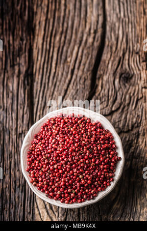Red peppercorn in bowl on oak table. Stock Photo