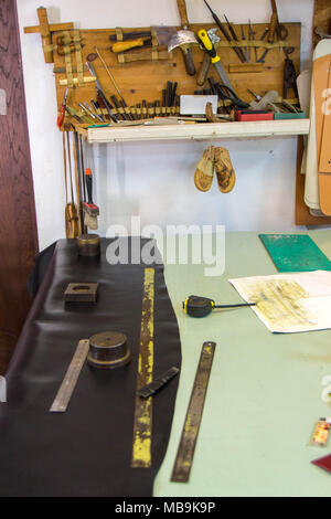 Leather craft or leather working. beautifully black tanned leather on leather craftman's work desk with working tools. Making leather belt Stock Photo