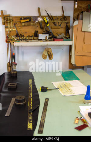 Leather craft or leather working. beautifully black tanned leather on leather craftman's work desk with working tools. Making leather belt Stock Photo