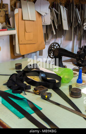 Leather craft or leather working. beautifully black tanned leather on leather craftman's work desk with working tools. Making leather belt Stock Photo