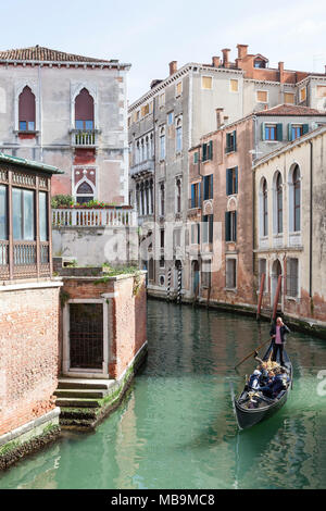 Rio San Polo, San Polo, Venice, Veneto Italy. Gondolier rowing tourists through a picturesque canal in his gondola  on a sightseeing tour Stock Photo