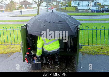 Glasgow, Scotland, UK 9th April. UK Weather: Work goes on as an engineer repairs the phone system under a brolly on a miserable wet day with squalid showers. Credit: gerard ferry/Alamy Live News Stock Photo