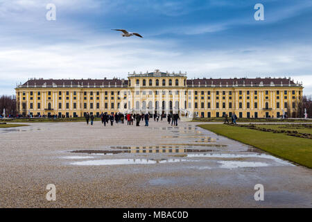 The garden park in Shonbrunn Palace (Wien) in rainy day with small puddles and large groups of tourists walking around Stock Photo