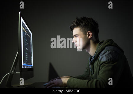 Young man hacking server in dark room Stock Photo