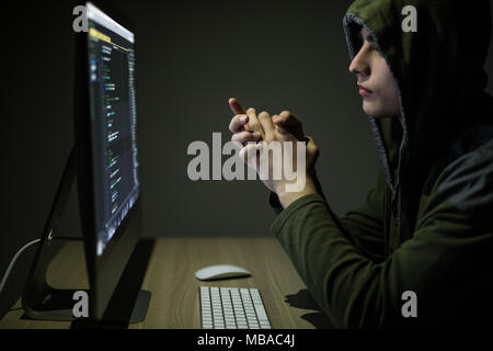 Man wearing hoodie hacking server in dark room Stock Photo
