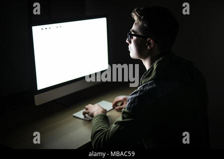 Handsome male programmer, IT person, hacker, works in computer on internet, black background. Stock Photo