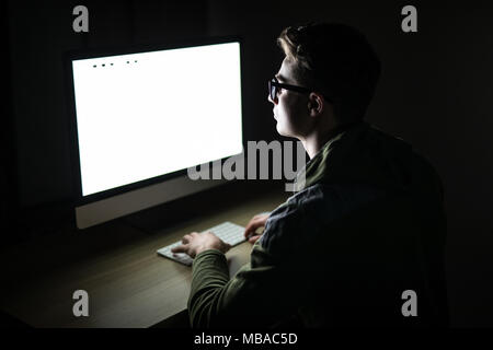 Handsome male programmer, IT person, hacker, works in computer on internet, black background. Stock Photo