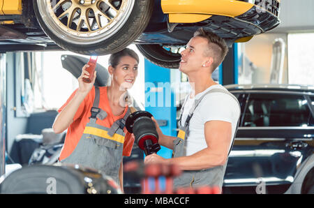 Experienced female auto mechanic with colleague a Stock Photo