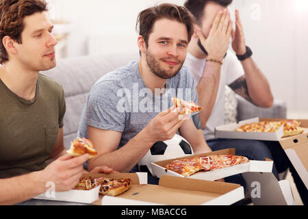 Happy male friends eating pizza and watching tv Stock Photo