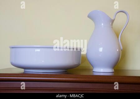 Pottery for facial wash and bowl on brown table with yellow wall in background Stock Photo