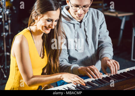 Piano teacher giving music lessons to his student