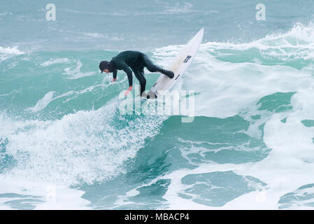 Surfing UK - a surfer in riding a wave in cold weather conditions. Stock Photo