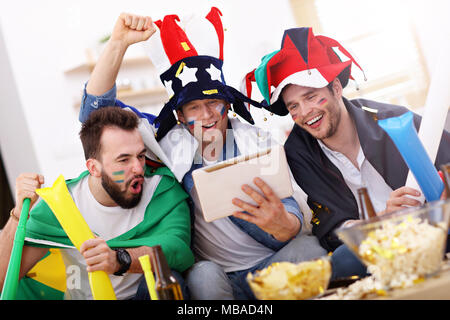 Happy male friends cheering and watching sports on tv Stock Photo