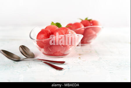 Watermelon cut with balls and served in glass dishes on wooden table Stock Photo