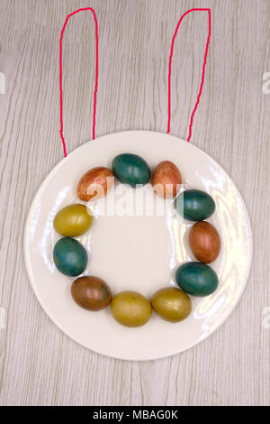 A nest with three colored Easter eggs and bunny ears at home on Easter day. Celebrating Easter at spring. Painting eggs Stock Photo