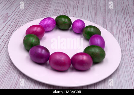 Painted eggs in wooden plate against rustic background Stock Photo
