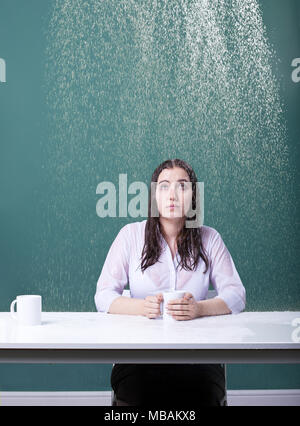 Woman sitting at a table indoors in the rain Stock Photo