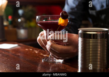 closeup of a bartender decorating a cherry vodka sour on the wooden bar counter Stock Photo