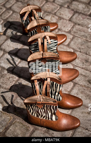 Six leather boots with wild zebra print are on display on the ground in a leather making souk in the medina of Marrakech, Morocco. Stock Photo