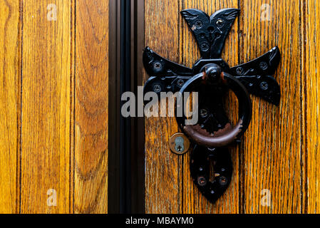 old black antique door knocker on wooden door Stock Photo