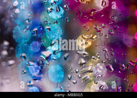 Whimsical abstract created with macro photographed water droplets on glass with multi color bokeh in background Stock Photo