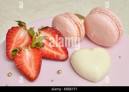 Mousse cake with pink mirror glaze, decorated with heart, macarons, and strawberry Stock Photo