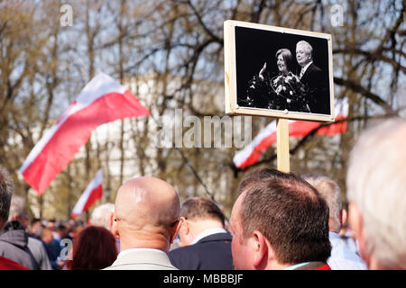 Warsaw, Poland - Tuesday 10th April 2018 - Poles queue as they arrive at Plac Pilsudskiego to take part in the commemoration service to remember the victims of the Smolensk ( Russia ) air crash in 2010 when a Polish Air Force VIP jet crashed killing 96 individuals including the then President of Poland Lech Kaczyński and his wife Maria shown in the portrait photo being held. Photo Steven May / Alamy Live News Stock Photo