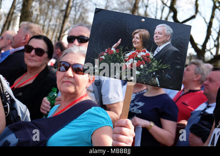 Warsaw, Poland - Tuesday 10th April 2018 - Poles arrive at Plac Pilsudskiego to take part in the commemoration service to remember the victims of the Smolensk ( Russia ) air crash in 2010 when a Polish Air Force VIP jet crashed killing 96 individuals including the then President of Poland Lech Kaczyński and his wife Maria ( shown in the portrait photo being held ). Photo Steven May / Alamy Live News Stock Photo