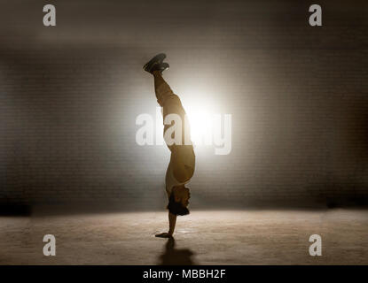 guy standing head over heels in balance-intensive position Stock Photo
