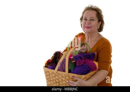 Portrait of smiling senior woman holding basket full of colourful yarn Stock Photo