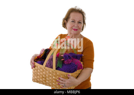 Studio portrait of cheerful senior lady with basket full of colourful yarn Stock Photo