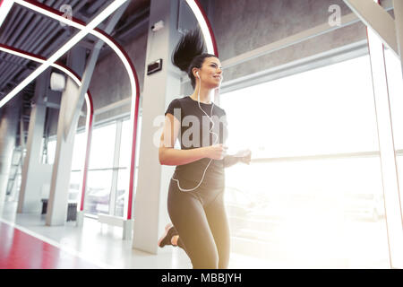 woman with earphones running on indoor track at gym Stock Photo