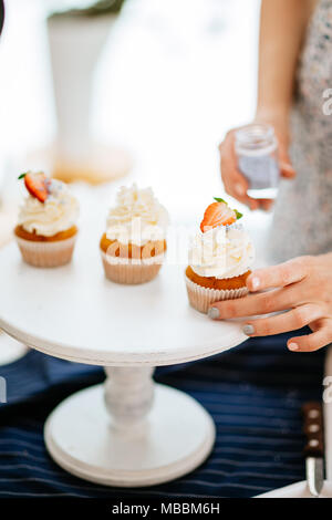 closeup of capcakes decorating with creamy icing and berries on white tray Stock Photo