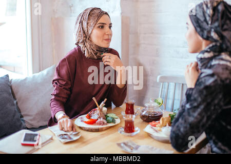 Two Muslim women in cafe, friends meeting Stock Photo