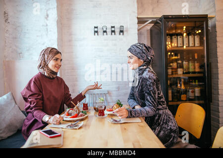 Two Muslim women in cafe, friends meeting Stock Photo