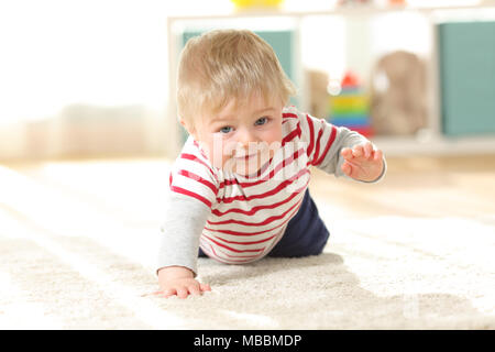 Happy baby crawling towards camera looking at you on the floor Stock Photo