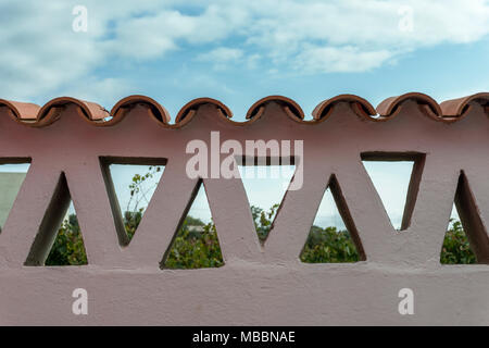 adobe wall with triangles and tiles that lets you see the vegetation and the sky with clouds Stock Photo