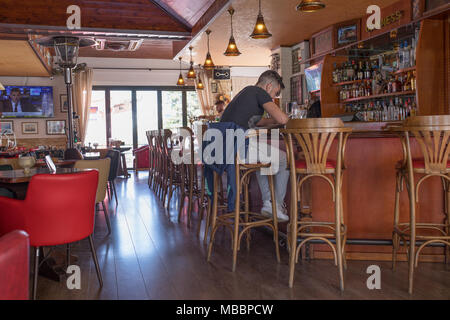 A man sitting in a modern pub. Malia, Crete / Greece. Stock Photo