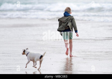 A young boy and his dog running on a beach. Stock Photo