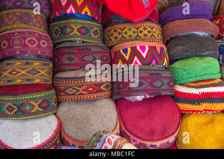 Unique, intricate, woven designs on an array of colorful, flat-topped caps for sale in a Manali market. Stock Photo