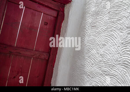 Freshly painted door and wall at Thiksay monastery near Leh, Ladakh.  Door is painted in traditional maroon-red while the clean walls are scalloped Stock Photo