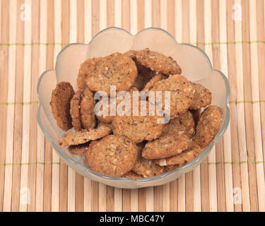 Crispy crunchy oatmeal raisin cookies in bowl on bamboo placemat Stock Photo
