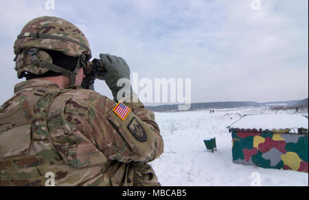 Yavoriv, Ukraine – U.S. Army Staff Sgt. Ronald Thomas, an infantryman assigned to the New York Army National Guard's 2nd Squadron, 101st Cavalry and deployed with the Joint Multinational Training Group – Ukraine, observes training conducted by Ukrainian Army Soldiers from 3rd Battalion, 14th Mechanized Brigade at the Yavoriv Combat Training Center (CTC) here Feb. 16. Currently the 3-14th is completing a training rotation at the CTC where they will be mentored by U.S., Canadian, Lithuanian, Polish, and U.K service members as they strive toward attaining their goal of achieving NATO interoperabi Stock Photo