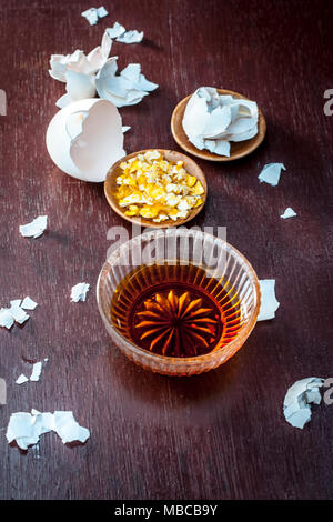 Close up of face pack consisting of egg peel and honey on a wooden surface in dark Gothic colors for soft and smoother skin. Stock Photo