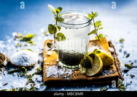 Indian popular summer drink SABJA NIMBUPANI/SWEET BASIL DRINK WITH LEMON and sugar in dark Gothic colors on a wooden surface.; Stock Photo