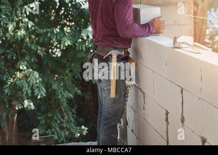 Mason worker building exterior walls, Industrial bricklayer installing bricks on construction site Stock Photo