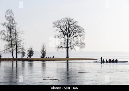 Schwerin, Germany. Silhouettes against the Sun of people, many trees, a small headland, and sportsmen in a kayak Stock Photo