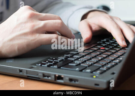 White man hands typing on a black notebook keyboard with natural light. Stock Photo