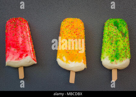 Three colorful popsicle shaped magnets souvenirs on grey background. Republic of Guinea flag. Stock Photo